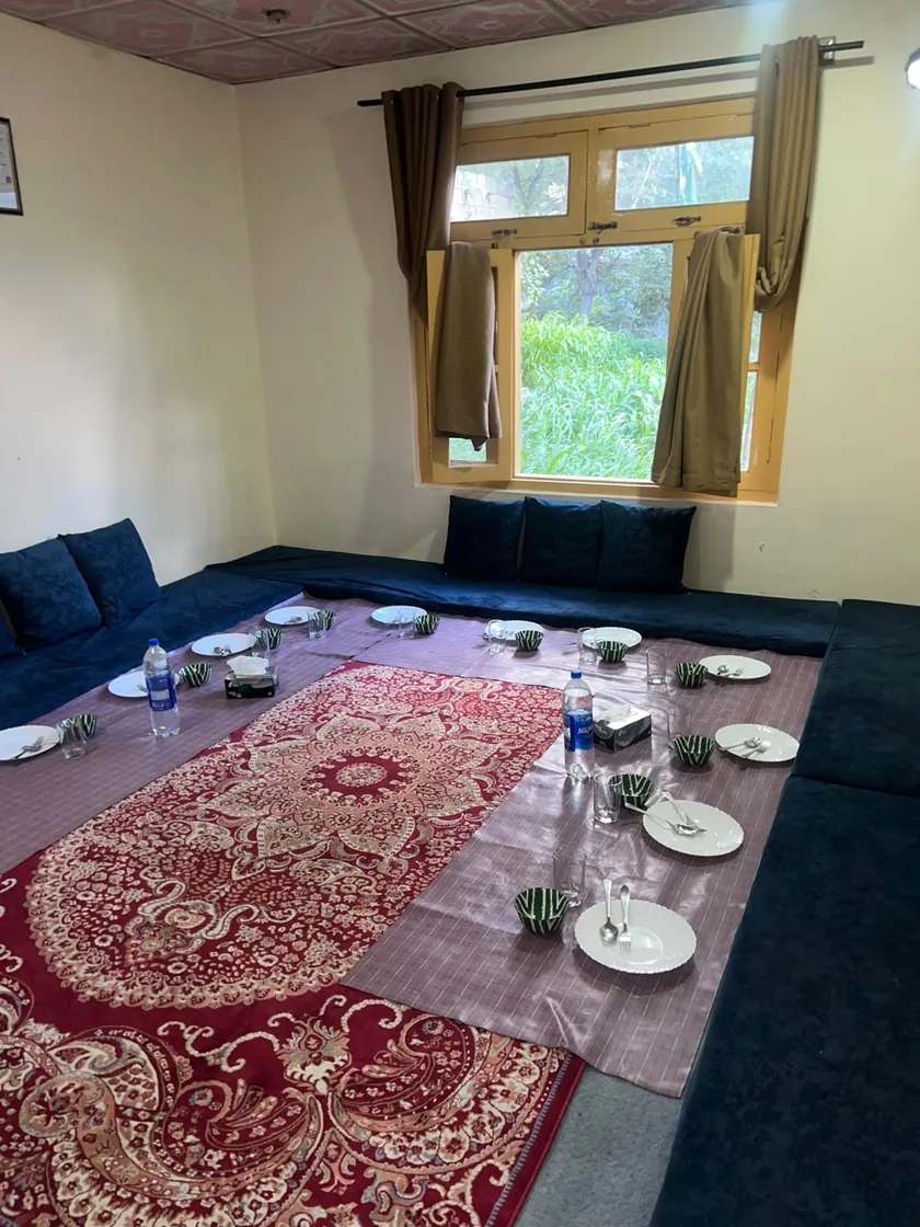 The dining room at Balti Cuisine: floor seating, a red carpet and a long cloth laid with plates